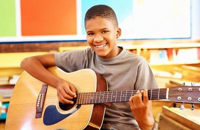 child wih a smile holding a guitar